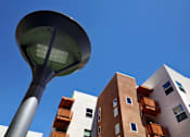 Thumbnail 14 of 94 - A street lamp stands in front of a building with orange balconies.