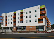 Thumbnail 3 of 94 - A modern apartment building with white walls and orange balconies.