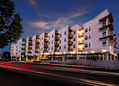 Thumbnail 10 of 94 - A modern apartment building with a white facade and balconies is illuminated at dusk.