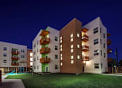 Thumbnail 13 of 94 - A modern apartment complex with balconies and lights on.