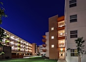 Thumbnail 2 of 94 - A modern building with a well-lit entrance and balconies.