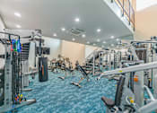 Thumbnail 27 of 38 - A gym with a variety of equipment including treadmills, weights, and exercise machines.