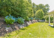 Thumbnail 37 of 44 - a garden with a stone retaining wall and blue flowers  at Cumberland Crossing, Cumberland