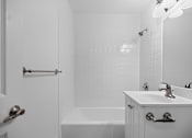 Thumbnail 34 of 52 - A white bathroom with a tub, sink, and mirror.