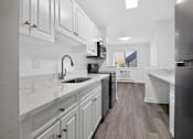 Thumbnail 49 of 52 - A kitchen with white cabinets and a black dishwasher.