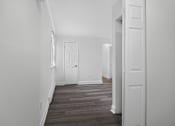 Thumbnail 48 of 52 - A hallway with a white door and a wooden floor.