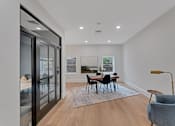 Thumbnail 21 of 38 - A modern dining room with a glass door and a grey sofa.
