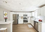 Thumbnail 3 of 21 - A renovated kitchen with white cabinets and appliances at Birchwood Hills Townhomes in Shirley, MA.