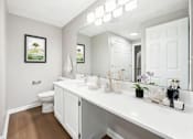 Thumbnail 7 of 21 - A renovated bathroom with a toilet, white vanity, sink, and mirror at Birchwood Hills Townhomes in Shirley, MA.