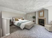 Thumbnail 10 of 21 - A bedroom with a large bed, carpet, a fireplace, and a chair at Birchwood Hills, Shirley MA.