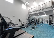 Thumbnail 30 of 38 - A gym with a variety of equipment including treadmills, stationary bikes, and weight machines.