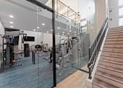 Thumbnail 29 of 38 - A gym with a staircase and exercise equipment.