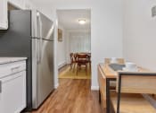 Thumbnail 26 of 57 - A kitchen with a refrigerator, a dining table with chairs, and a countertop. at South Winds Apartments, Fall River, 02720