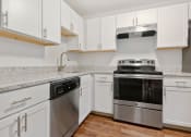 Thumbnail 28 of 57 - A modern kitchen with white cabinets and stainless steel appliances. at South Winds Apartments, Fall River, 02720