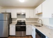 Thumbnail 29 of 57 - A kitchen with a stainless steel refrigerator and white cabinets. at South Winds Apartments, Massachusetts