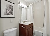 Thumbnail 19 of 20 - A bathroom with a white tub, sink, and shower curtain.