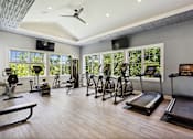Thumbnail 7 of 20 - A spacious home gym with a variety of exercise equipment and a ceiling fan.