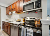 Thumbnail 11 of 20 - A kitchen with a stove top oven and a microwave above it.