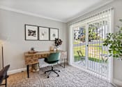 Thumbnail 9 of 20 - A room with a desk and a chair with a white fence outside.