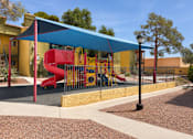 Thumbnail 13 of 23 - A playground with a red slide and a blue canopy.