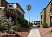 Thumbnail 12 of 23 - A long concrete pathway leads through a landscaped courtyard between two buildings.