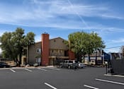 Thumbnail 9 of 23 - A parking lot with a building in the background.