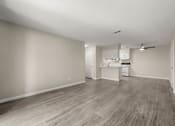 Thumbnail 12 of 24 - an empty living room and kitchen with wood flooring and white walls