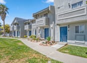 Thumbnail 6 of 18 - a row of townhomes with blue doors and grass and a sidewalk