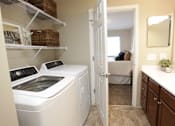Thumbnail 10 of 15 - A white washing machine and dryer in a small laundry room.