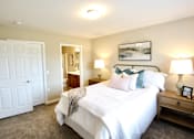 Thumbnail 6 of 15 - A bedroom with a large bed, a nightstand, and a door.