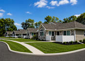 Thumbnail 7 of 42 - Apartment buildings with beige siding and porches with white fence.