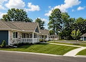 Thumbnail 9 of 42 - An apartment building with blue siding and rock siding and white railing on a front porch.