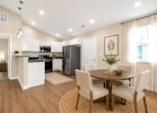 Thumbnail 16 of 42 - An open kitchen and dining area with white cabinets, black countertop and stainless steel appliances.