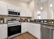 Thumbnail 27 of 42 - A modern kitchen with white cabinets and stainless steel appliances.