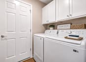Thumbnail 30 of 42 - A laundry are with a washer and dryer and white cabinets.