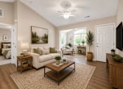Thumbnail 26 of 42 - A living room with a couch, end tables and a coffee table in front of a sunroom.