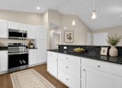 Thumbnail 35 of 42 - A kitchen with white cabinets, black countertop, wood plank floor and stainless steel appliances.