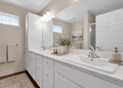 Thumbnail 39 of 42 - A bathroom with double sinks and white cabinets and countertops