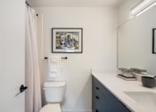 Thumbnail 16 of 39 - a bathroom with a white toilet next to a sink with a mirror above it
