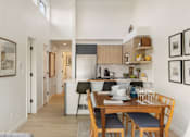 Thumbnail 27 of 39 - a dining area with a wooden table and chairs and a kitchen in the background