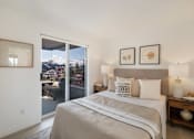 Thumbnail 18 of 39 - a bedroom with a large bed and a sliding glass door leading to a balcony