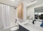 Thumbnail 15 of 39 - a bathroom with a white sink and toilet next to a bathtub with a shower curtain