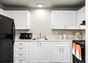 Thumbnail 11 of 15 - A black refrigerator is in a kitchen with white cabinets.