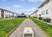Thumbnail 4 of 15 - A long concrete walkway leads to a building with a blue roof.