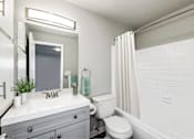Thumbnail 7 of 15 - A white bathroom with a toilet, sink, and shower.