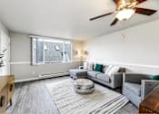 Thumbnail 9 of 15 - A living room with a grey couch and a wooden side table.
