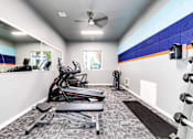 Thumbnail 10 of 15 - A gym room with a treadmill, exercise bike, and weights.