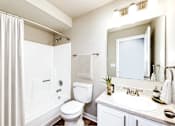 Thumbnail 4 of 15 - A white bathroom with a toilet, sink, and mirror.