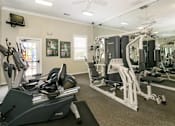 Thumbnail 7 of 13 - A gym with a variety of equipment including treadmills, weights, and a television. at The Dawson Cartersville in Cartersville, GA 30191