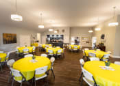 Thumbnail 10 of 31 - a large dining room with yellow table cloths and white chairs